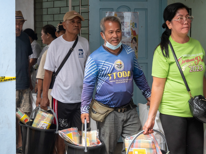 Tricycle driver Emilio Ornopia (in blue) smiles as he carries his relief goods.