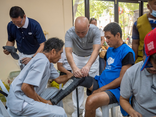 Jose Waldemar Rico, prosthetic technician (left, seated), ensures that the prosthesis fits comfortably for the recipient.