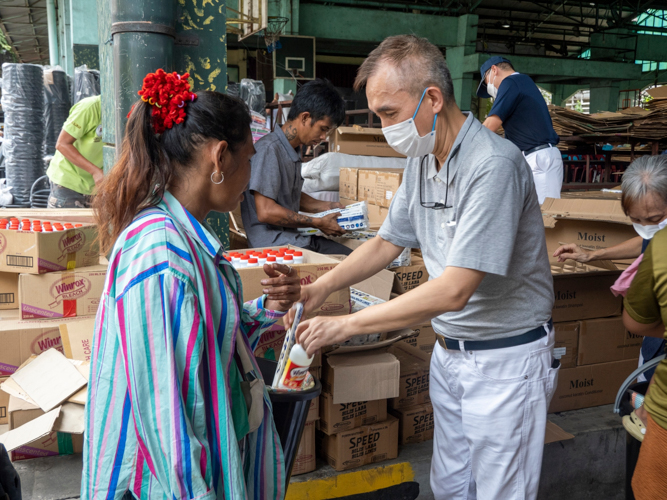 A Tzu Chi volunteer distributes relief goods to the beneficiary.