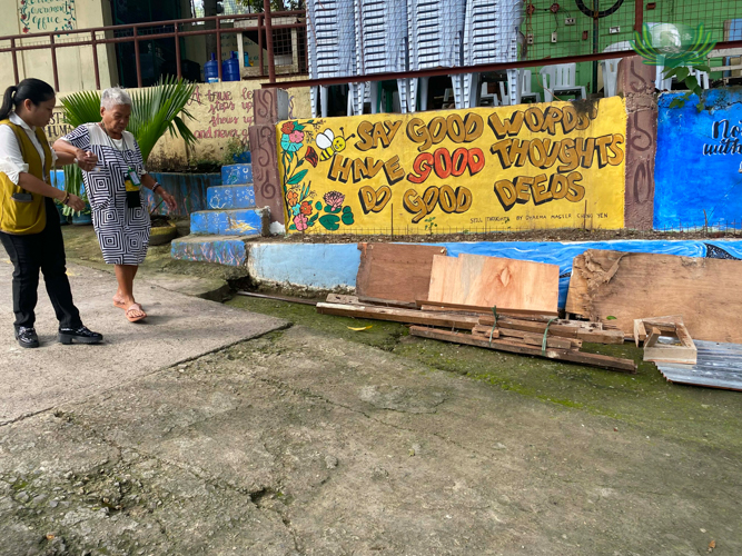 At Pulpogan National High School, where Tzu Chi scholars painted one of Dharma Master Cheng Yen’s well-loved aphorisms on a wall, a volunteer helps a woman walk an uneven ground.