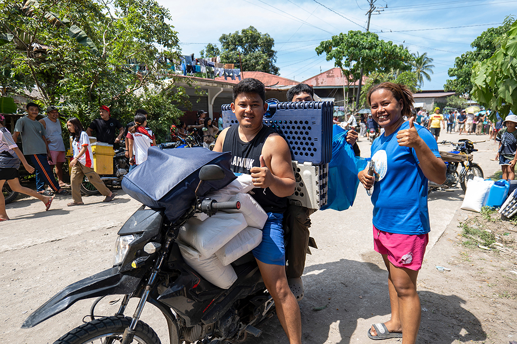 Household members say “thank you” Tzu Chi style with their thumbs as they get ready to leave with their relief items. 