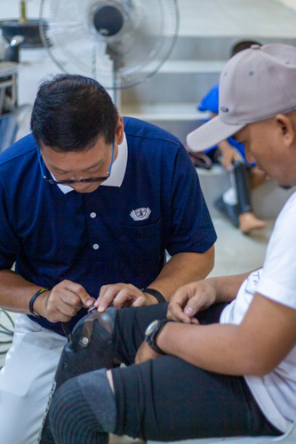 Tzu Chi Zamboanga Liaison Officer Dr. Anton Mari Lim checks a beneficiary’s prosthesis.