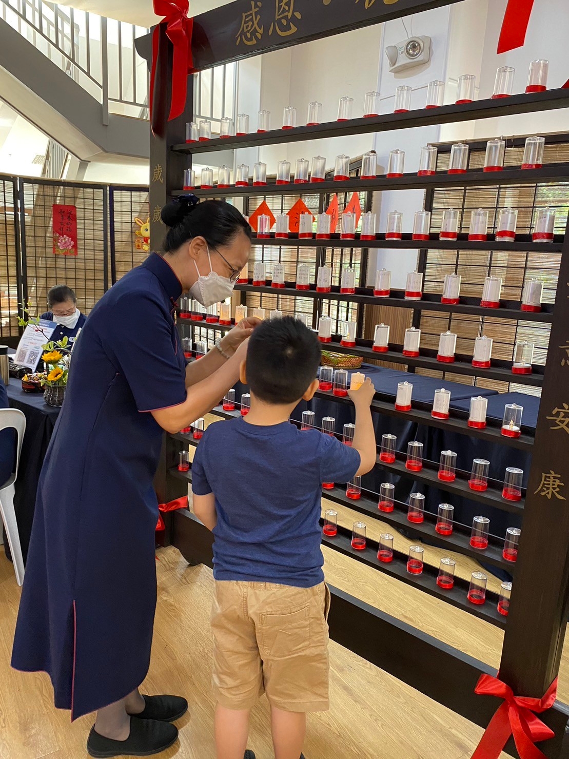 A volunteer helps a child place his handwritten wish in a candle holder. 【Photo by Matt Serrano】