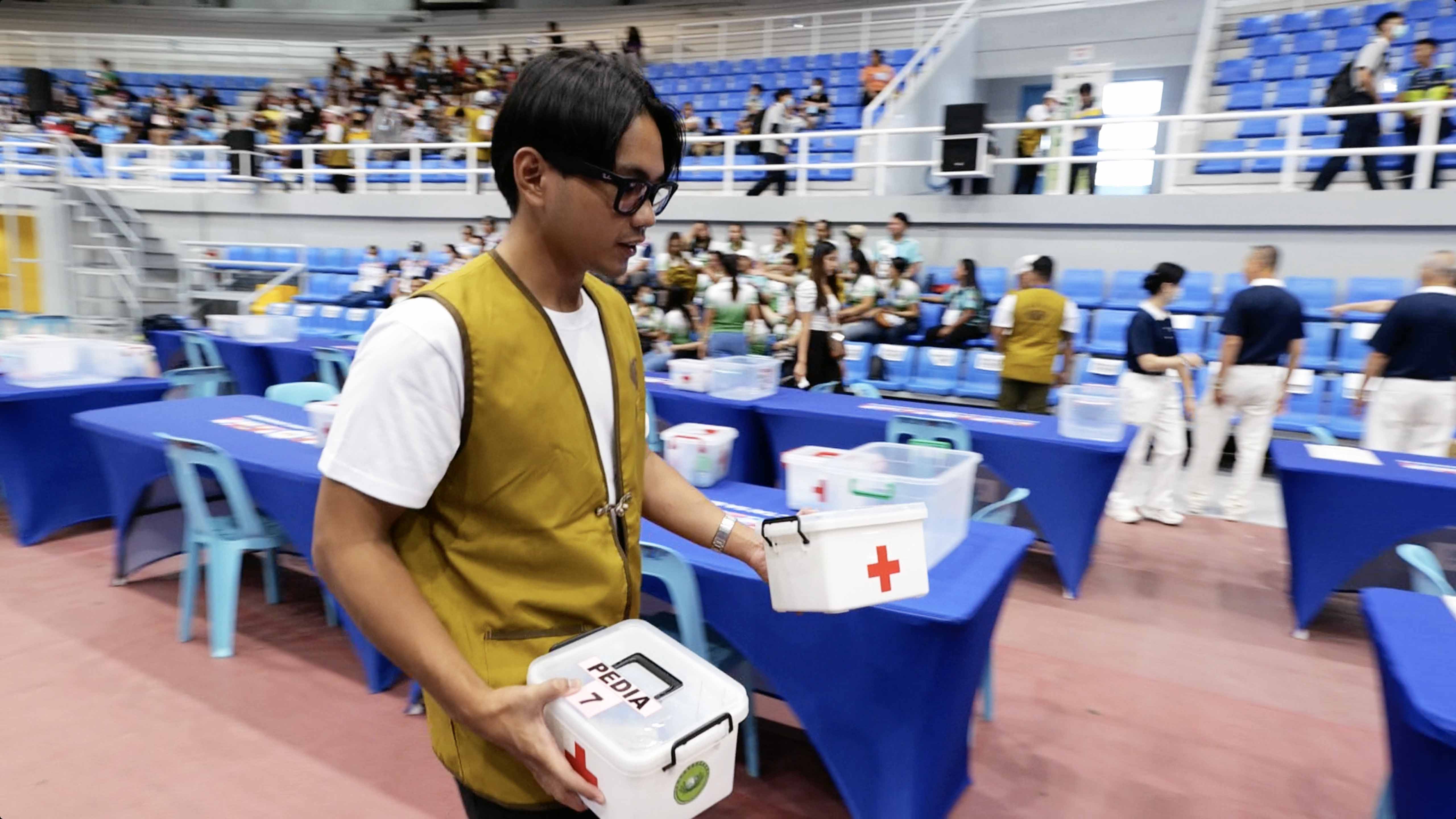 Gio Pamintuan prepares and arranges medical supplies on each table for the doctors at the medical mission venue.