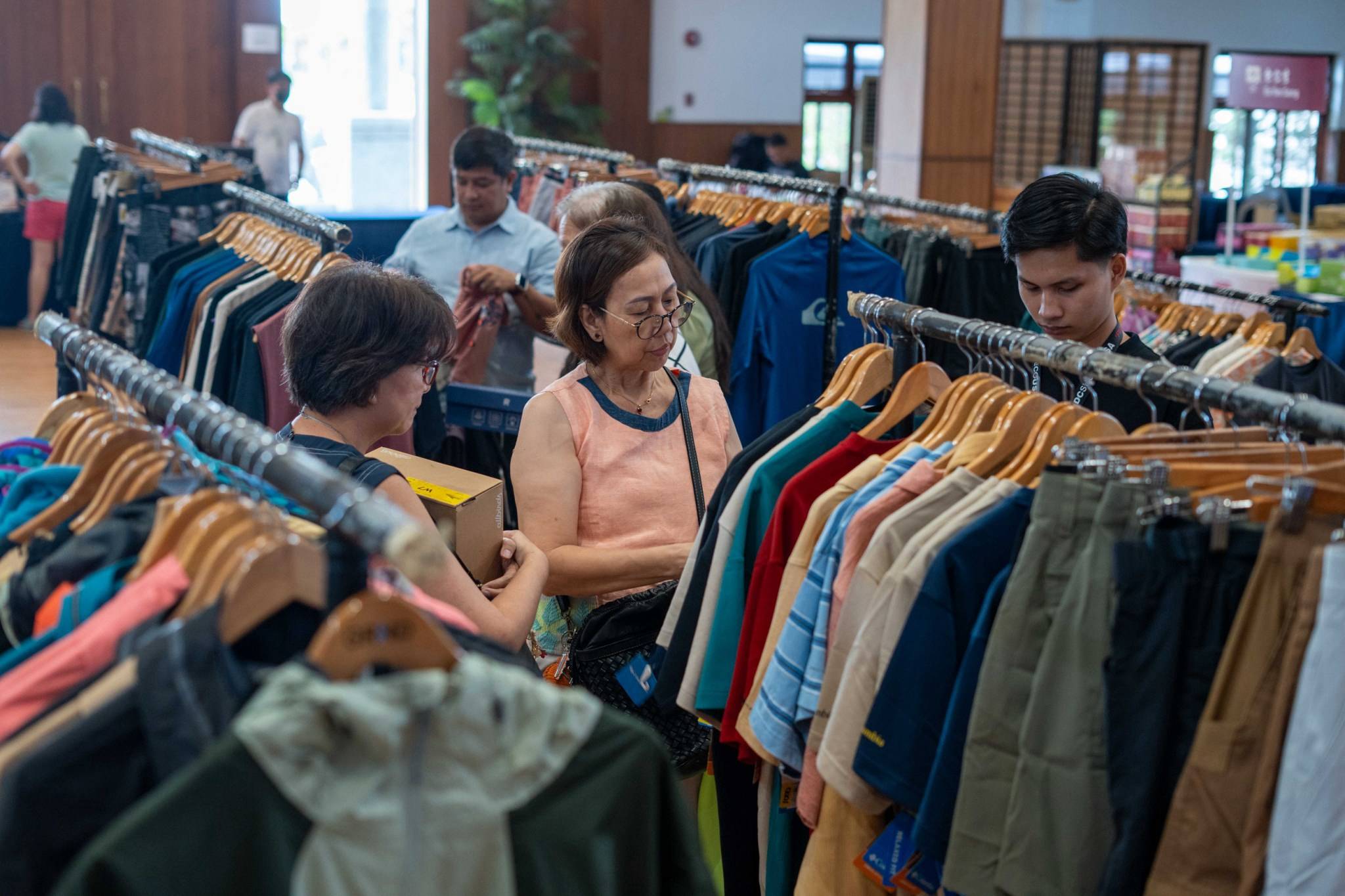 Friends and families gather inside the Jing Si Hall, browsing through a wide selection of premium clothes on sale.