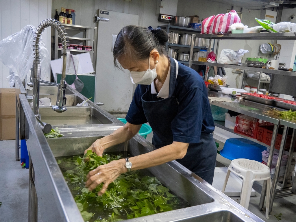 A Tzu Chi volunteer ensures the cleanliness of the vegetables during preparation by washing them thoroughly.