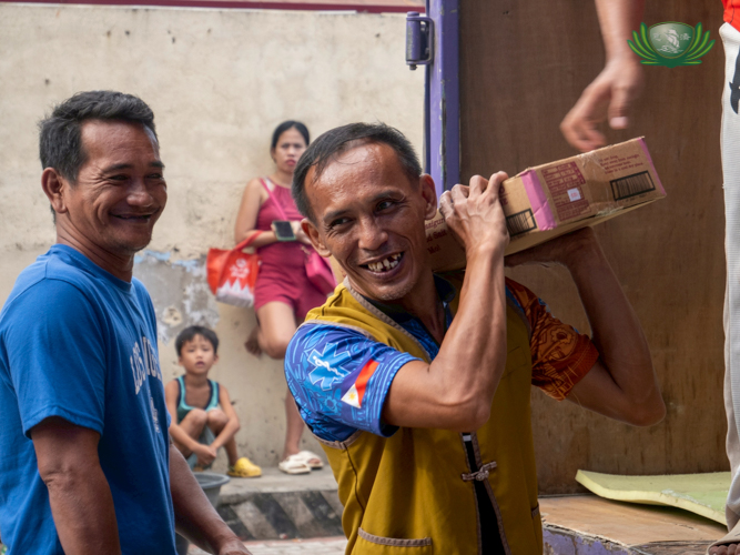 LGU volunteers assist in unloading grocery supplies for affected families ahead of distribution. 