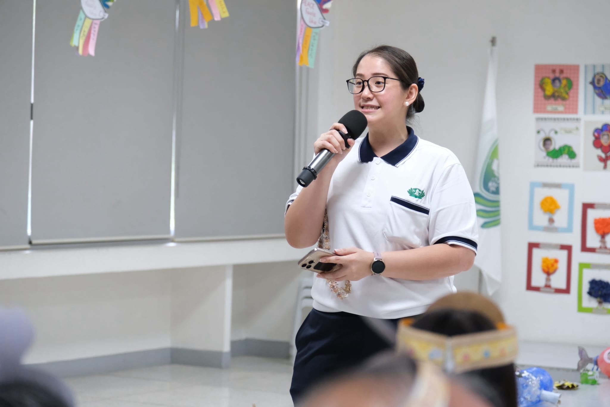 Directress Jane Sy opens the celebration, commending parents for guiding their children and creating meaningful cultural displays together. 
