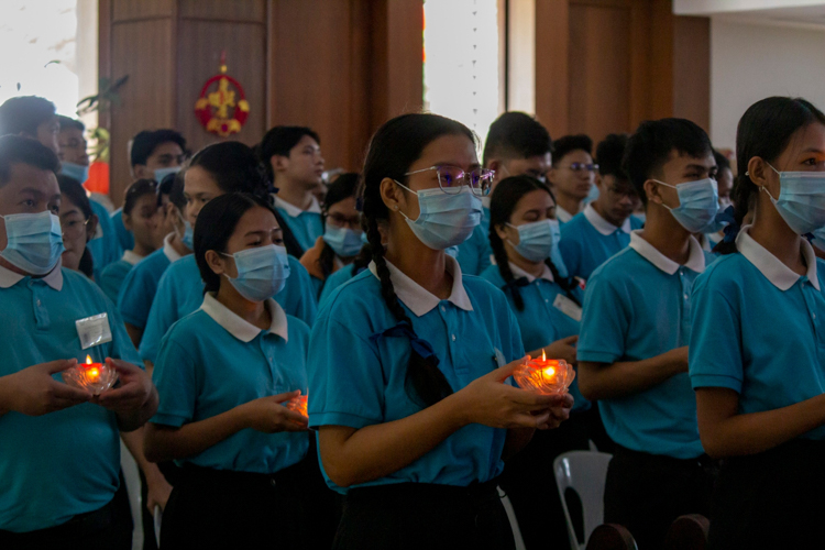 Tzu Chi scholars hold candles as they pray.