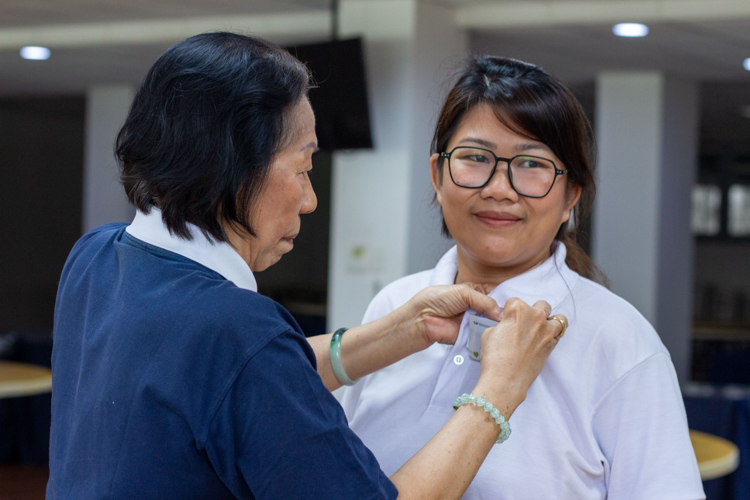 A Tzu Chi volunteer for 14 years, Catherine Ching welcomes her niece Annie Ong to the two-day New Volunteers Camp by assisting her with her name tag.  