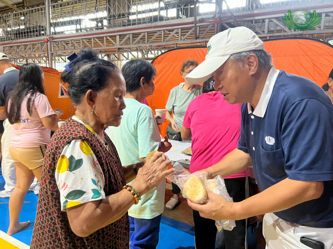 A woman helps herself to bread offered by volunteer Johnny Kwok.