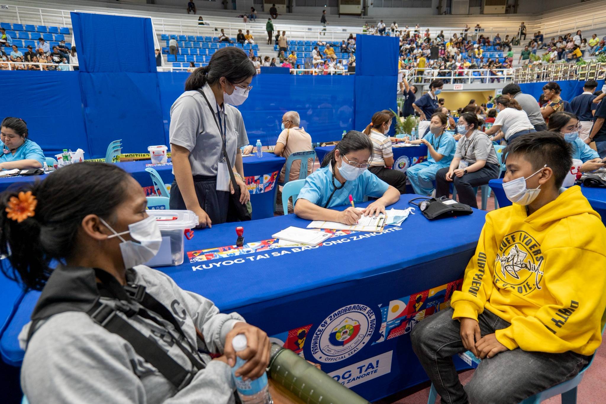 A TCU student (standing) closely observes as a TIMA doctor assesses patients. 