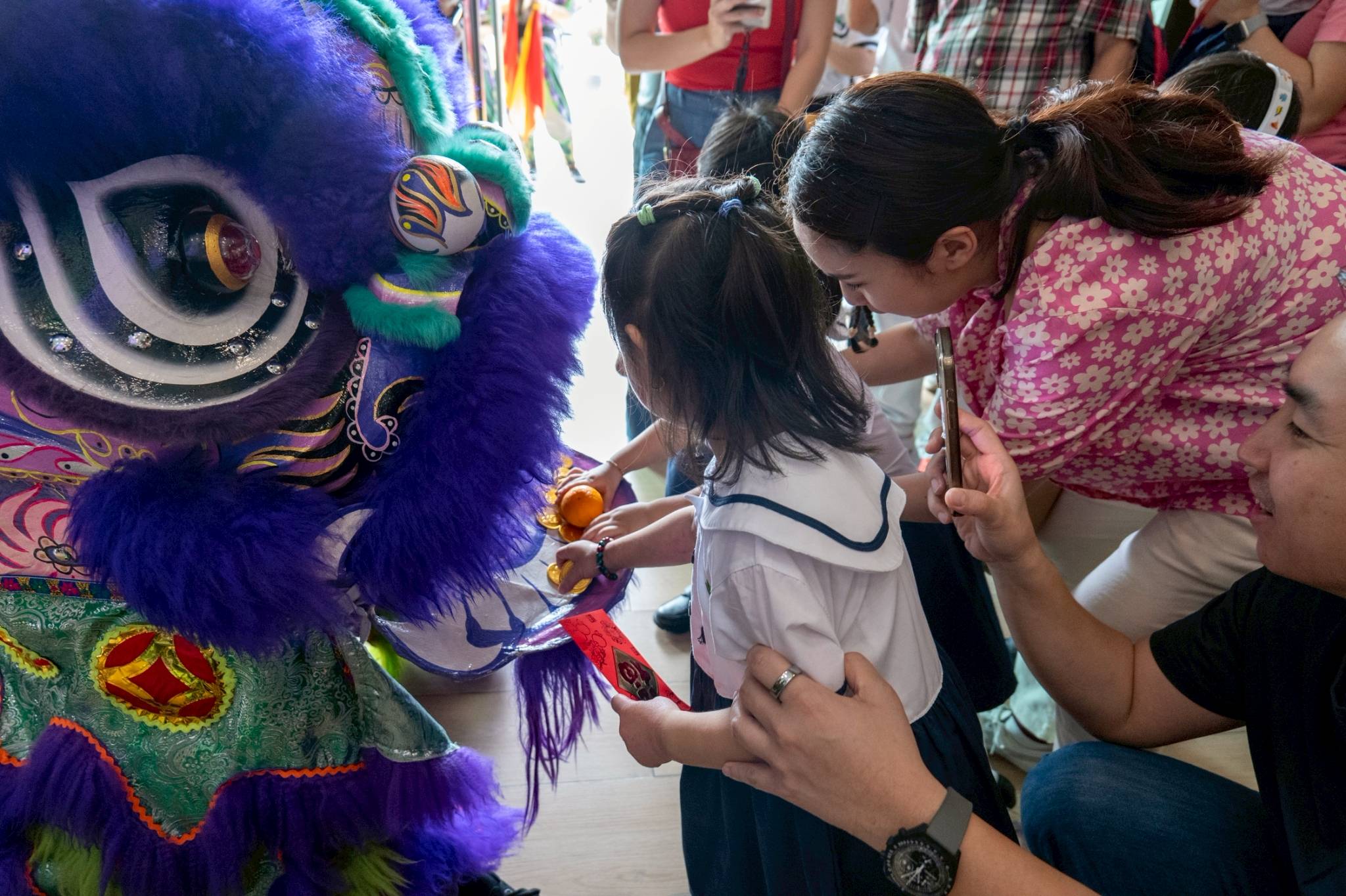 Parents and children joined in presenting red envelopes to the lion, a gesture of prosperity for the new year.