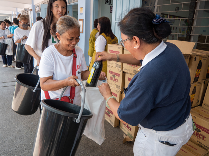 A beneficiary happily receives kitchen essentials for her home.