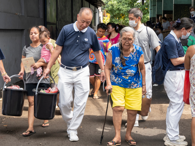 A Tzu Chi Volunteer assists a beneficiary in carrying the relief goods.