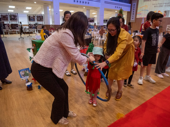 Parent Raquel Tan (in yellow) enjoys a game of passing the hula hoop with fellow parents.