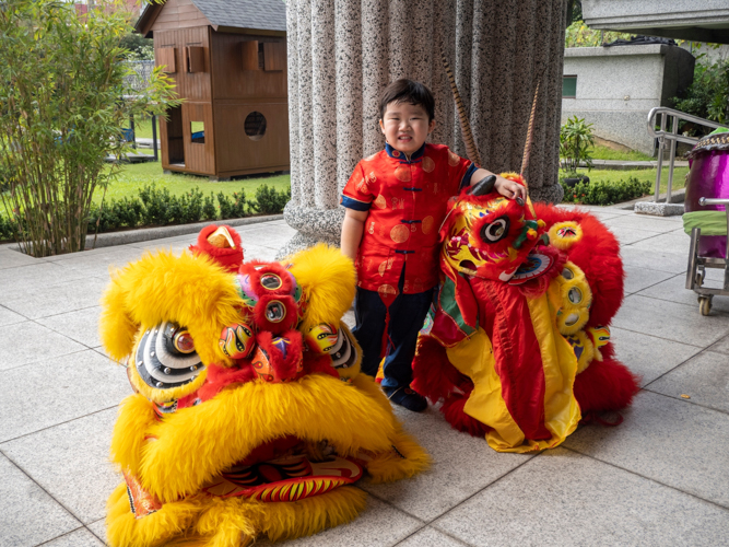 A preschooler caps the Chinese New Year celebration with a picture next to the lion dancers’ headdresses.