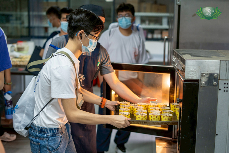A camp participant loads a tray of muffins into the oven for baking.