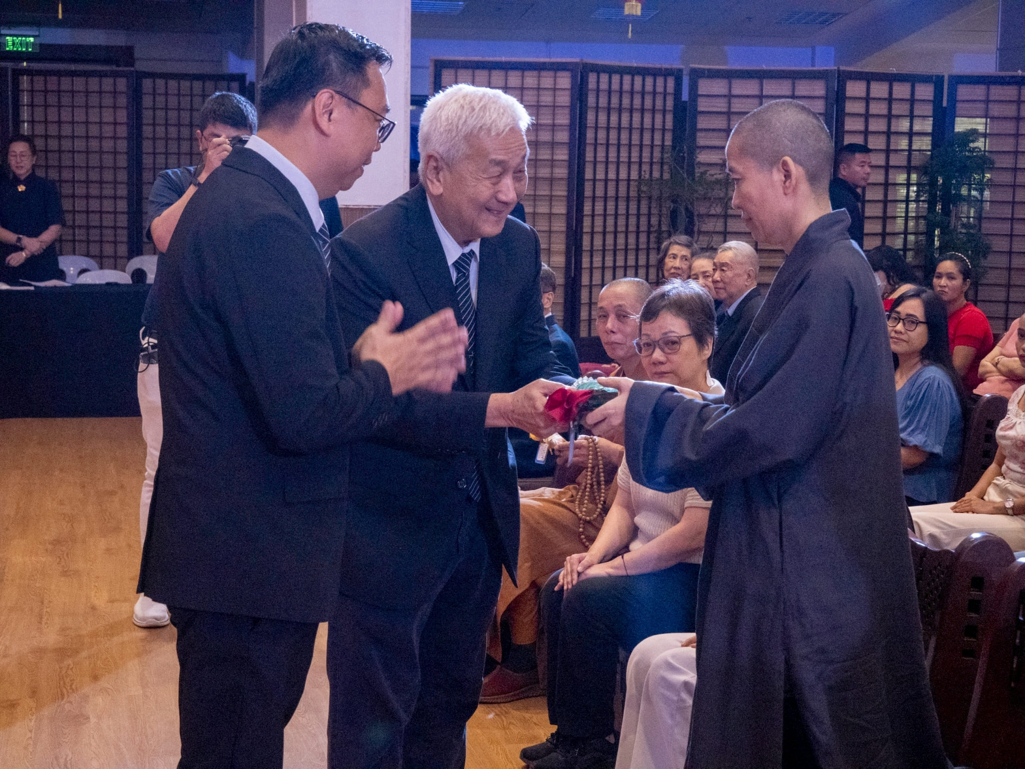 A Buddhist monk receives a red envelope and other tokens from Tzu Chi Philippines CEO Henry Yuñez (center) and Tzu Chi volunteer Wilson Hung. 