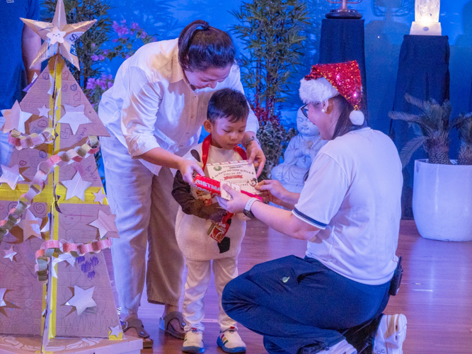 A student receives an award for his creative eco-friendly Christmas tree, made using recycled boxes and adorned with hand-drawn artworks.