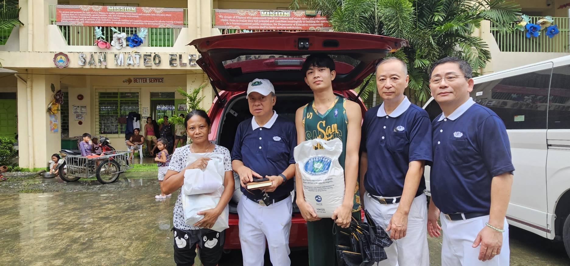 Scholar Axcel Rivera (center) claimed his basic provisions from Tzu Chi volunteers outside San Mateo Elementary School. 