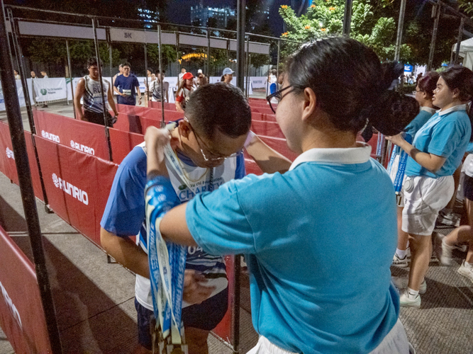 Tzu Chi scholars assist in awarding medals to runners at the finish line.