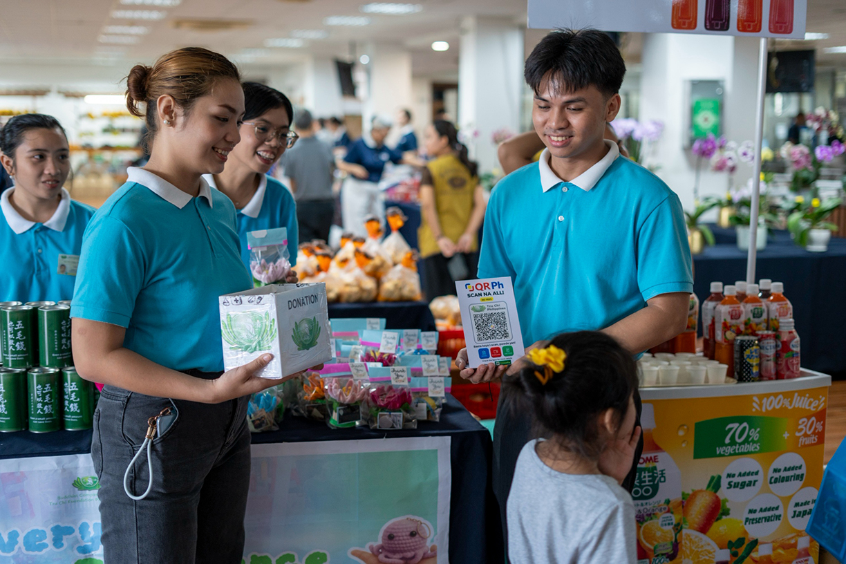 A heartwarming moment of generosity as a young exhibitor steps forward to drop a contribution into Tzu Chi scholars' donation box.