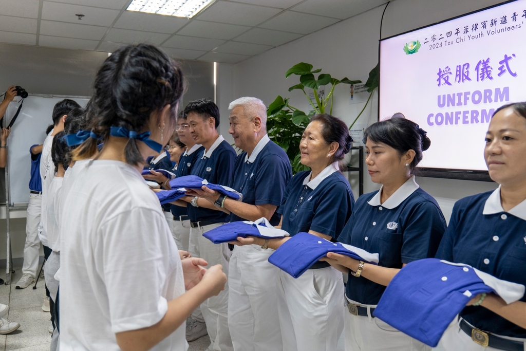 Tzu Chi volunteers formally turn over the purple blue uniforms to Tzu Chi Youth volunteers.