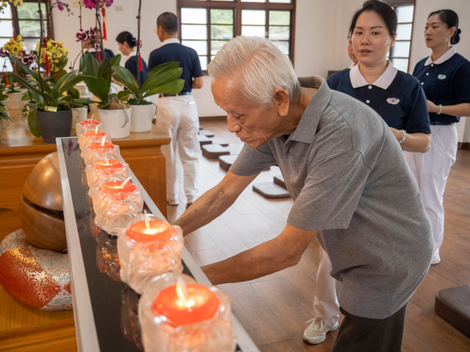 Tzu Chi volunteers and guests place their candle offerings before the Buddhist altar in the Jing Si Abode.