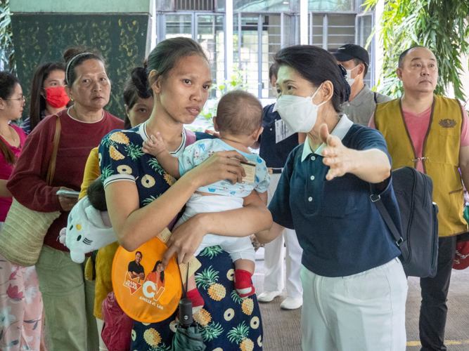 Tzu Chi volunteer Woon Ng assists a beneficiary in receiving relief stubs.