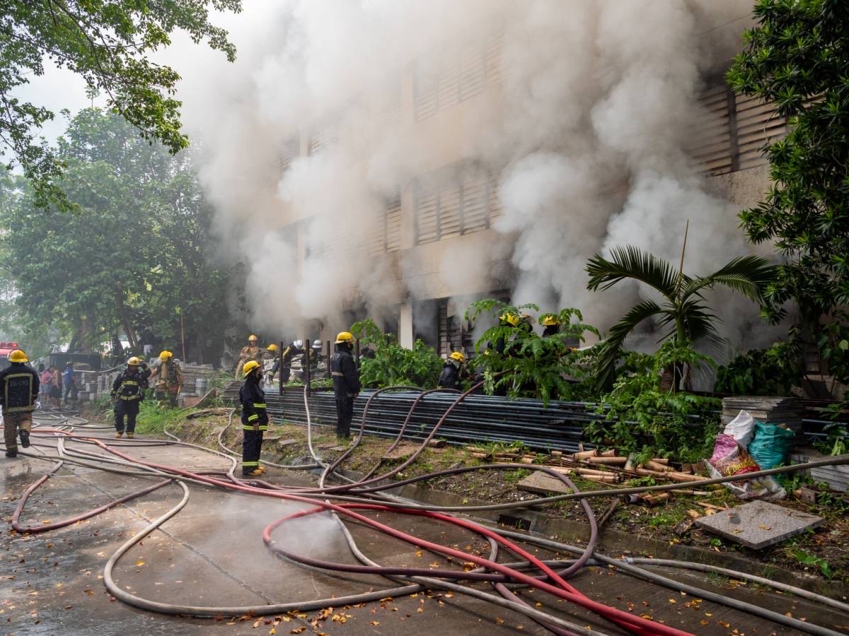 Firefighters manning hoses as thick smoke bellows out of the windows. 【Photo by Daniel Lazar】