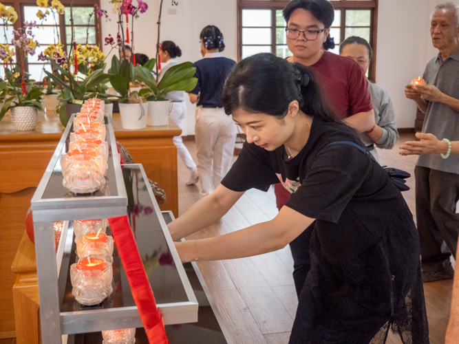 Tzu Chi volunteers and guests place their candle offerings before the Buddhist altar in the Jing Si Abode.