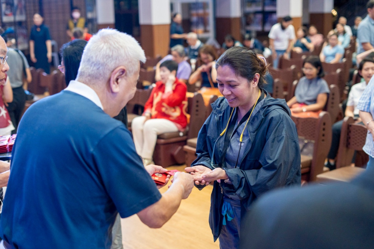 Guests receive angpao, a red envelope containing commemorative coins from Dharma Master Cheng Yen.