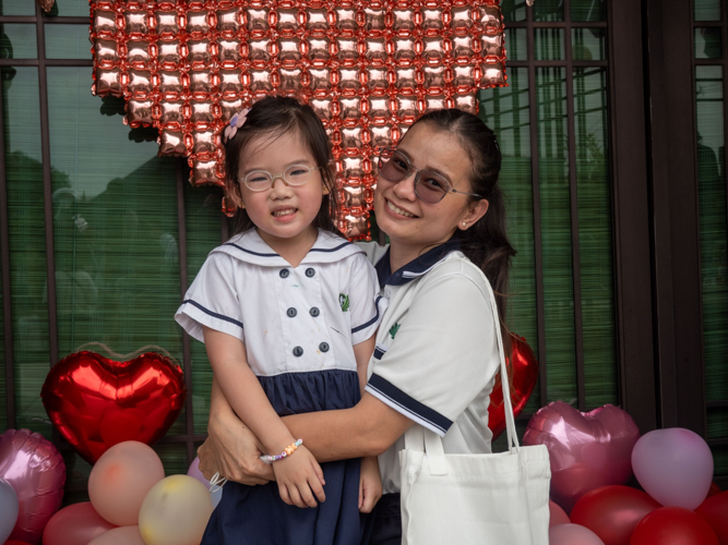 Pre-kindergarten teacher MJ Seno takes a photo with one of her students. 