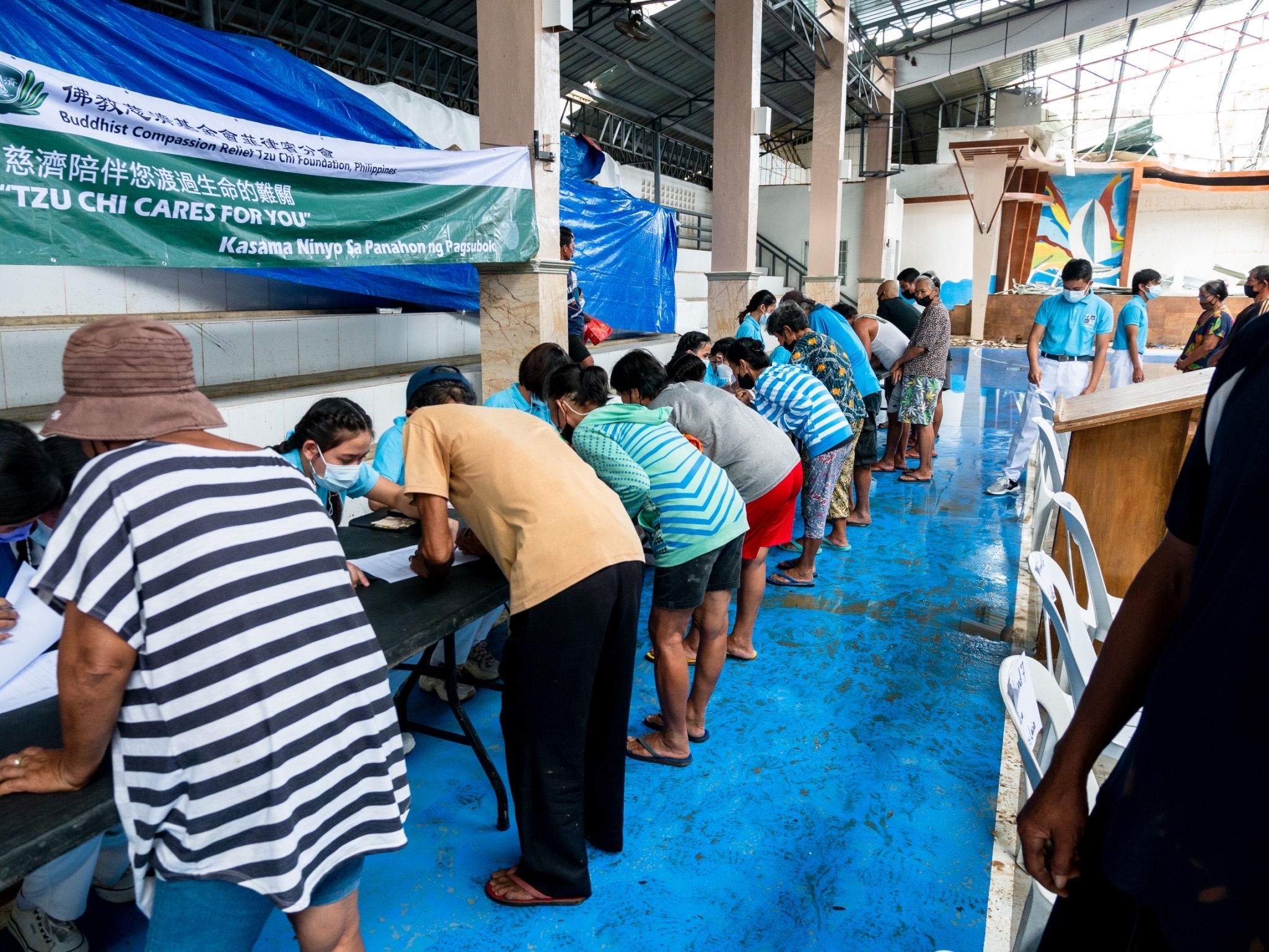 Beneficiaries present their Relief Distribution Family Card to volunteer scholars to claim their rice relief. 【Photo by Daniel Lazar】