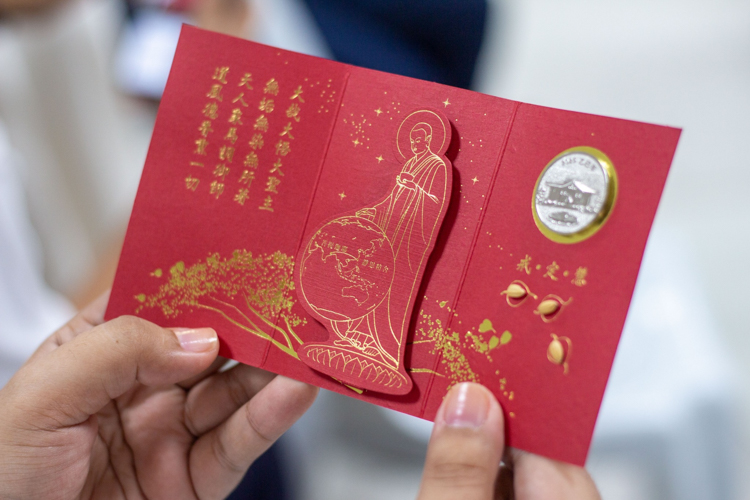 Tzu Chi Philippines CEO Henry Yuñez distributes angpao containing commemorative coins and rice seeds.