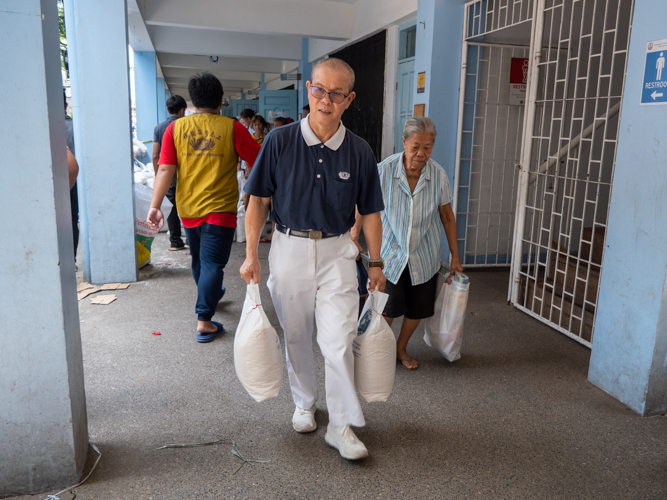 Tzu Chi volunteer Manny Go carries sacks of rice for the beneficiaries.