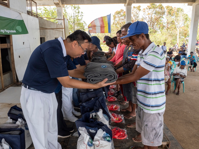 Beneficiaries receive blankets made from recycled plastics from Tzu Chi volunteers.