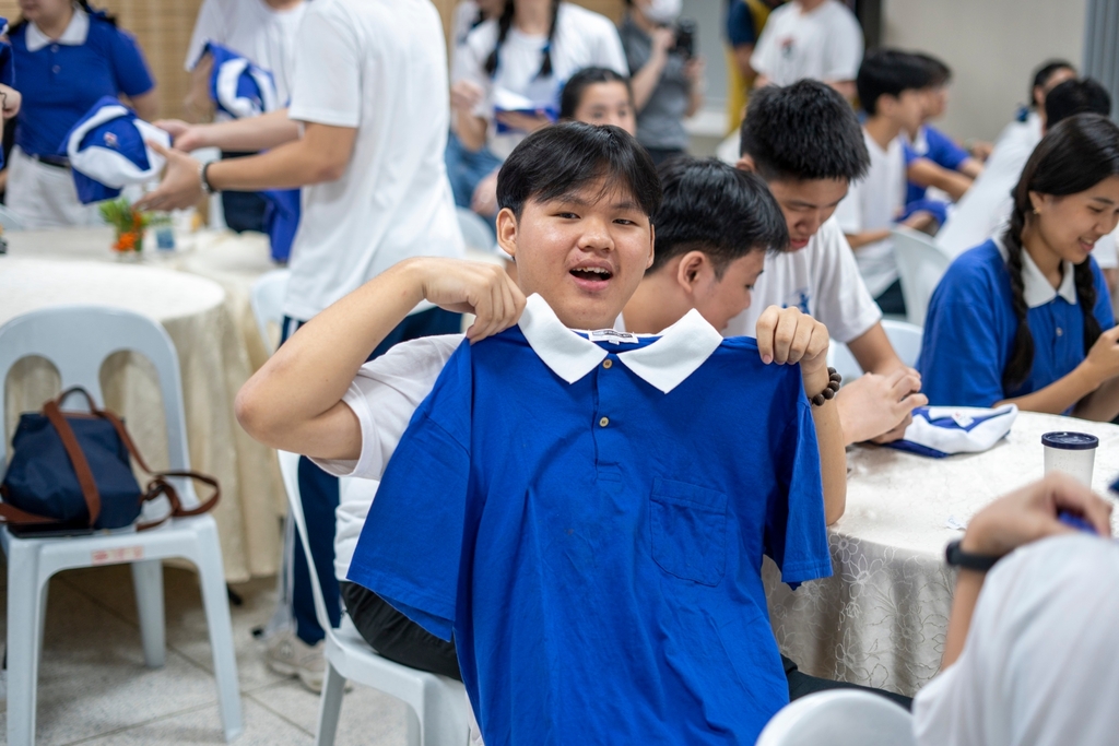 John Carlo Caedo happily shows off his Tzu Chi Youth uniform.