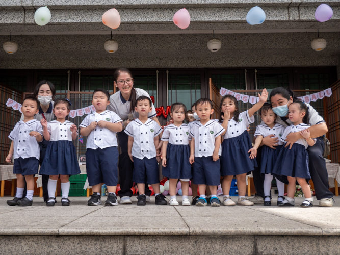 Nursery students, together with teacher Marian “Yani” Carpo (second row, leftmost),  Directress Jane Sy (second row, center), and teacher Mary Ann Rodriguez (second row, rightmost) pose for a photo after their performance. 