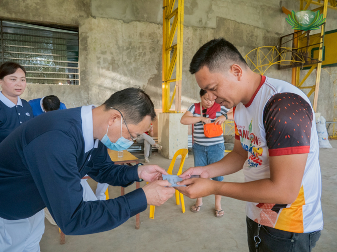Tzu Chi volunteer Willy Sy bows as he hands over financial assistance to a beneficiary.