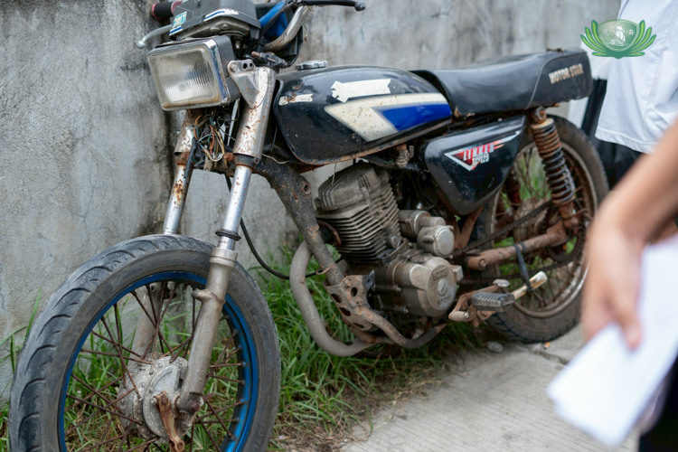 Rone Arpon’s motorcycle is parked on the side of the road, unused due to the damages to his sidecar after the heavy rains and flooding.