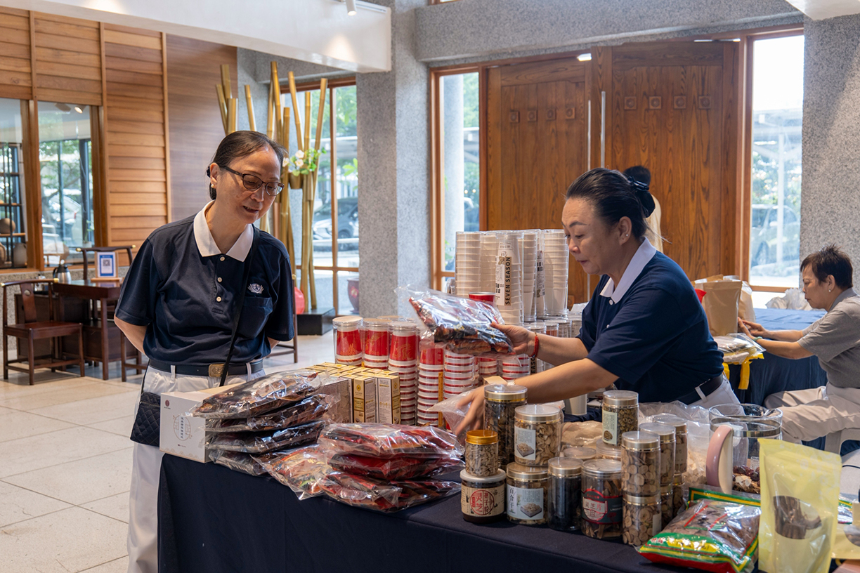 Carefully setting up the display, volunteers organize a colorful assortment of herbal products and plant-based snacks for visitors to explore.