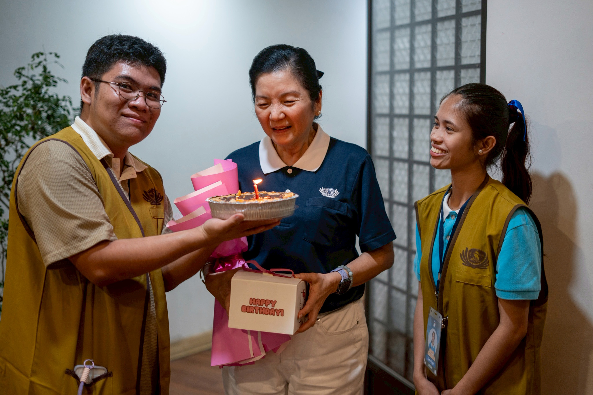 Leandro Peter Joshua Taton presents a cake to Rosa So, head volunteer for the educational and medical assistance programs and a July celebrant, as camp head Heart Baquilar looks on. 