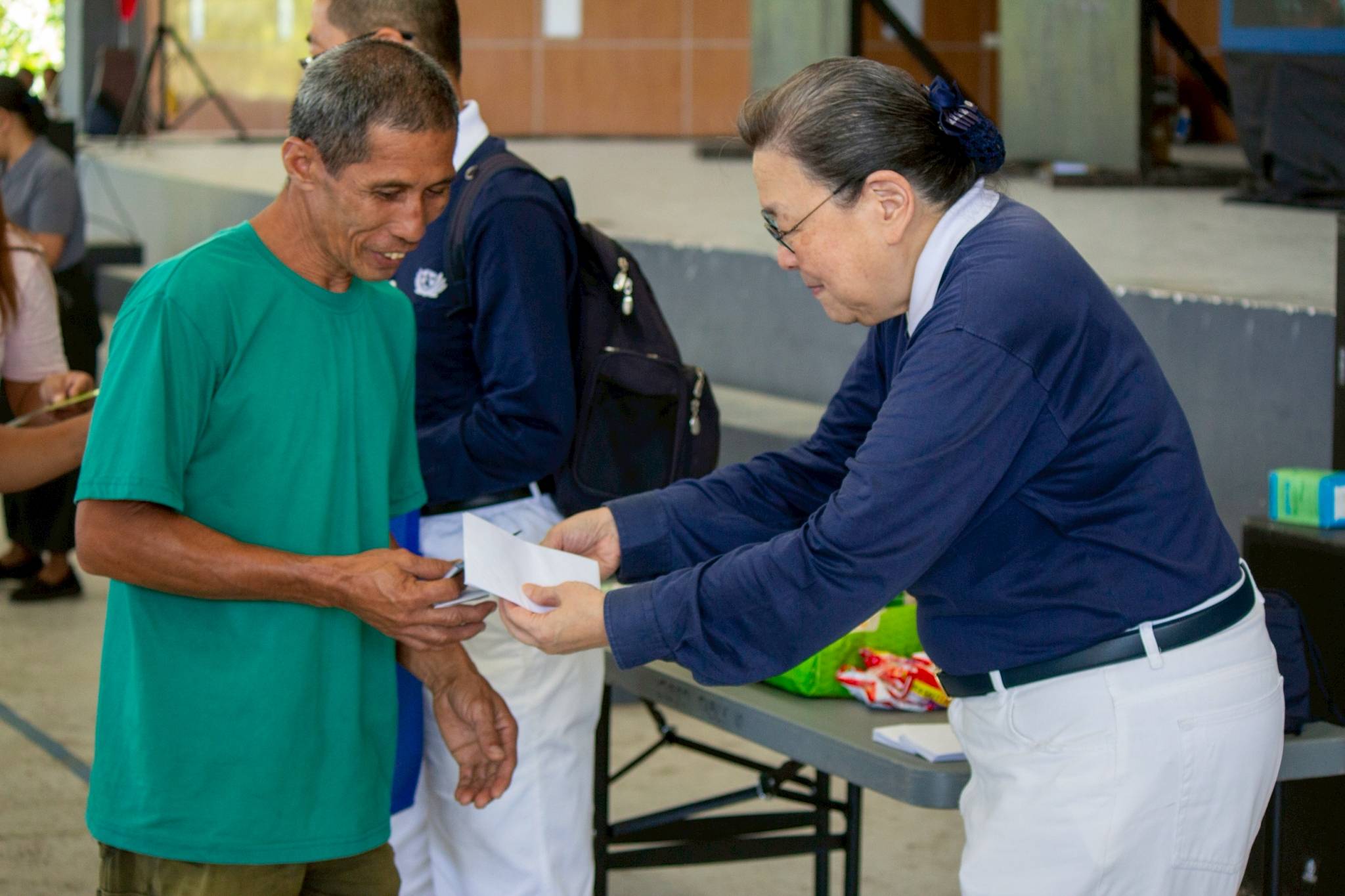 Tzu Chi volunteer Judy Lao assists in distributing gift checks  aid to the beneficiaries.