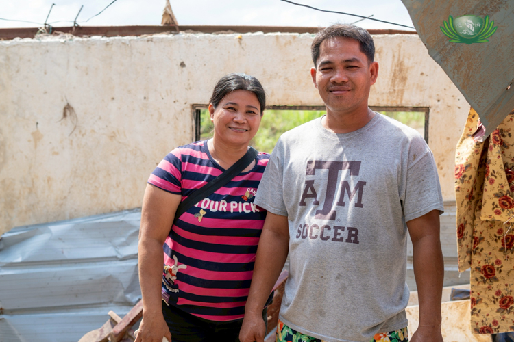 Alberto Ego-ogan (right) poses for a photo with his wife, in the area where their home once stood.