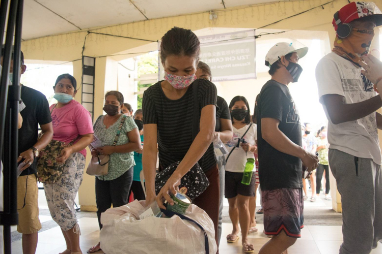 Rose Marie Araban drops coins from her Tzu Chi coin bank into a collection jar. “This pandemic is just a challenge in our lives,” she says. “God has not abandoned us.” 【Photo by Don Lopez】