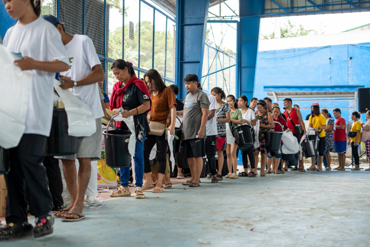 Relief is given in an orderly manner, with beneficiaries using their pail given by Tzu Chi to collect items from volunteers.