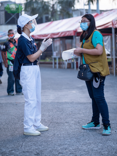 Universidad de Manila social work major Catherine Jill Cilla (right) gets last-minute instructions from a Tzu Chi volunteer before the start of the Caloocan North relief distribution for tricycle drivers. 【Photo by Daniel Lazar】