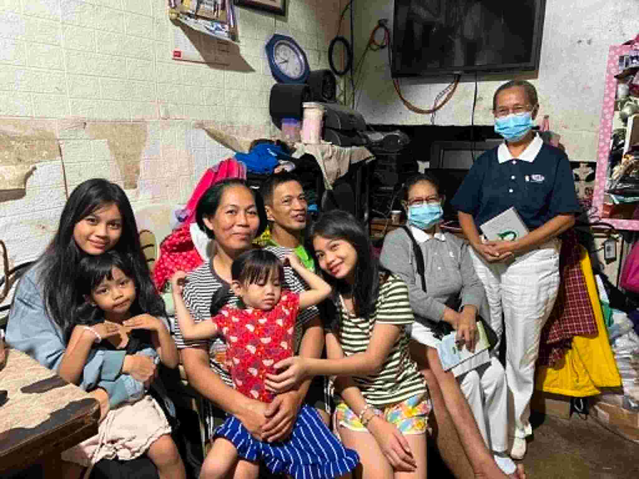 Seated next to her parents, Jennilyn and Ariel, Cyrin Joy Dizon (first from left) hugs her little sister during a home visit conducted by Tzu Chi volunteers (far right). 